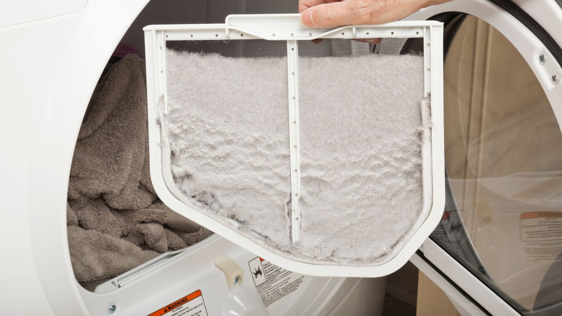 Lint-covered dryer filter being removed during laundry maintenance