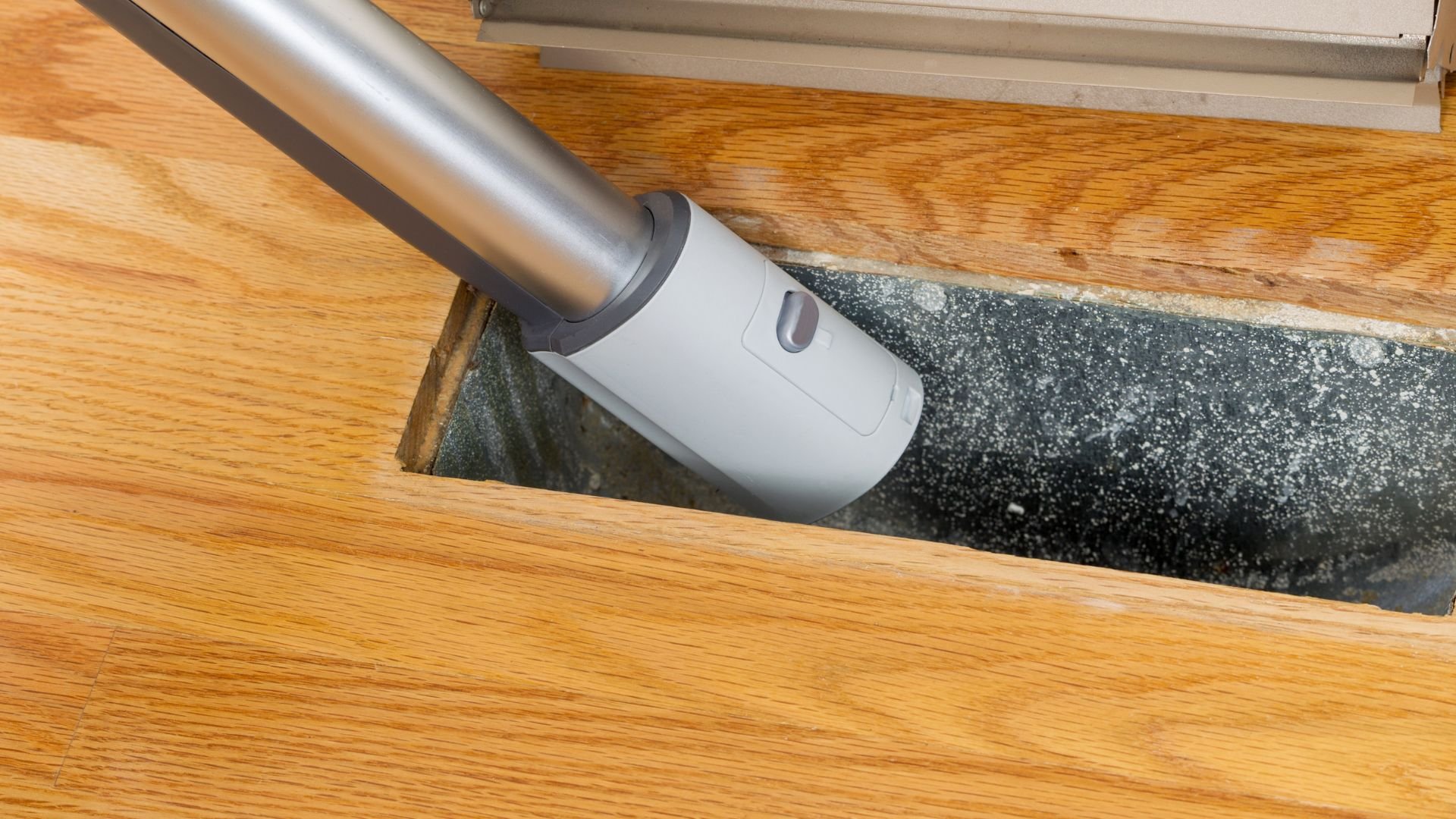 Vacuum cleaner attachment cleaning dust from between wooden floor boards