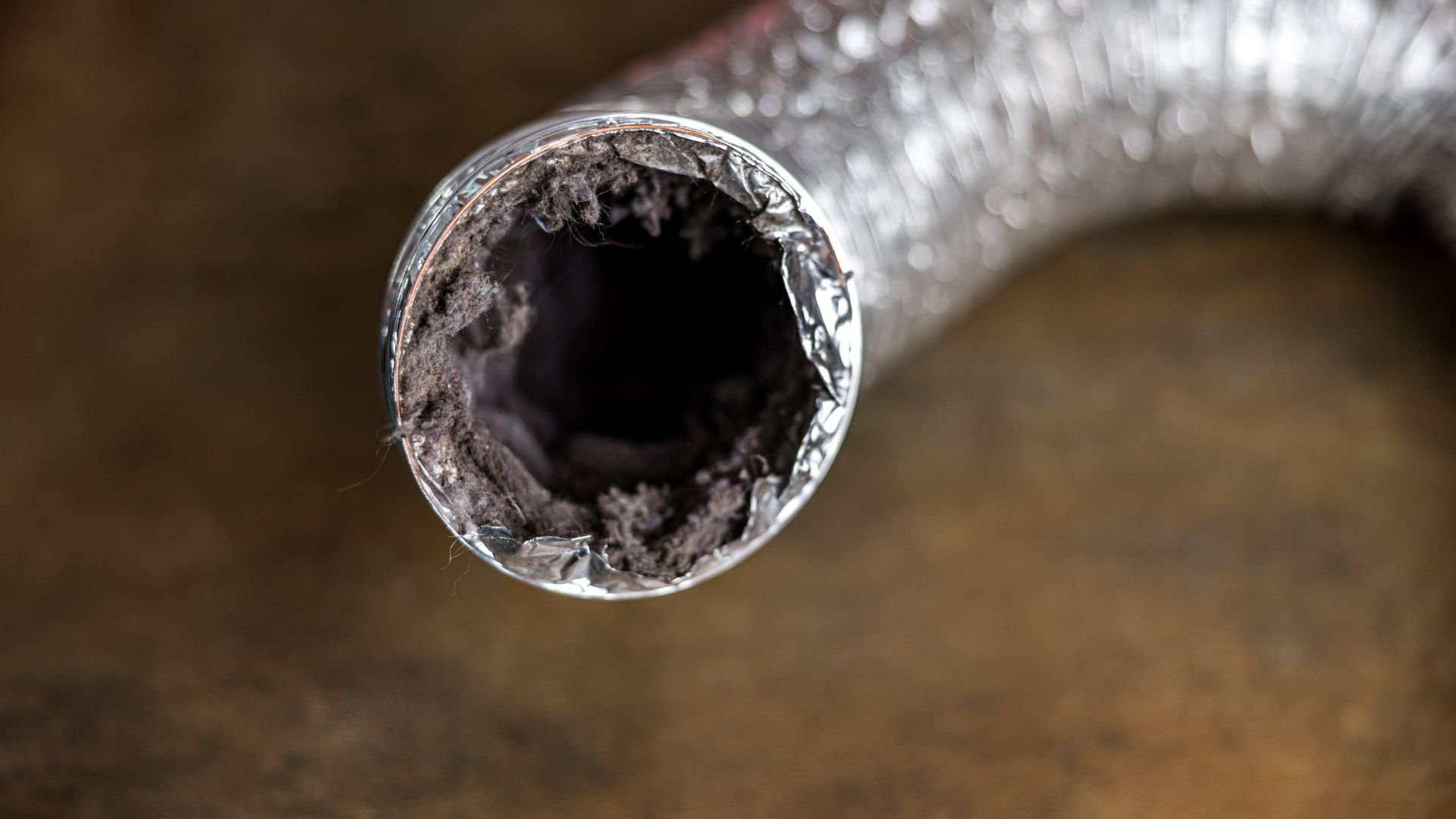 Dusty, damaged dryer vent tube with lint buildup viewed from end