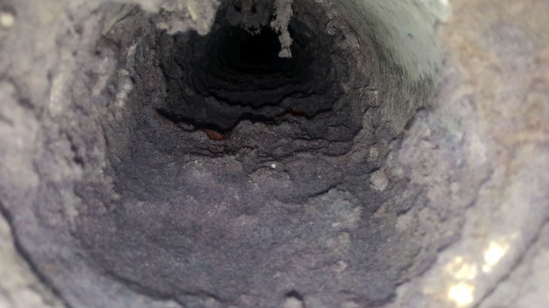 Dark, textured interior of a narrow tunnel or pipe with rocky walls